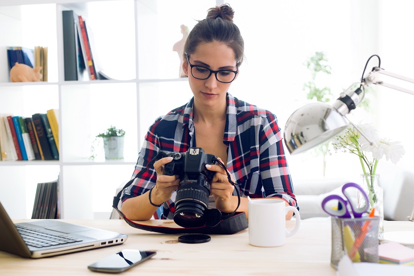 Young woman photographer checking previews on camera in the stud